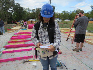 Madeline checking the wall raising plans at a Habitat build in Bryan.