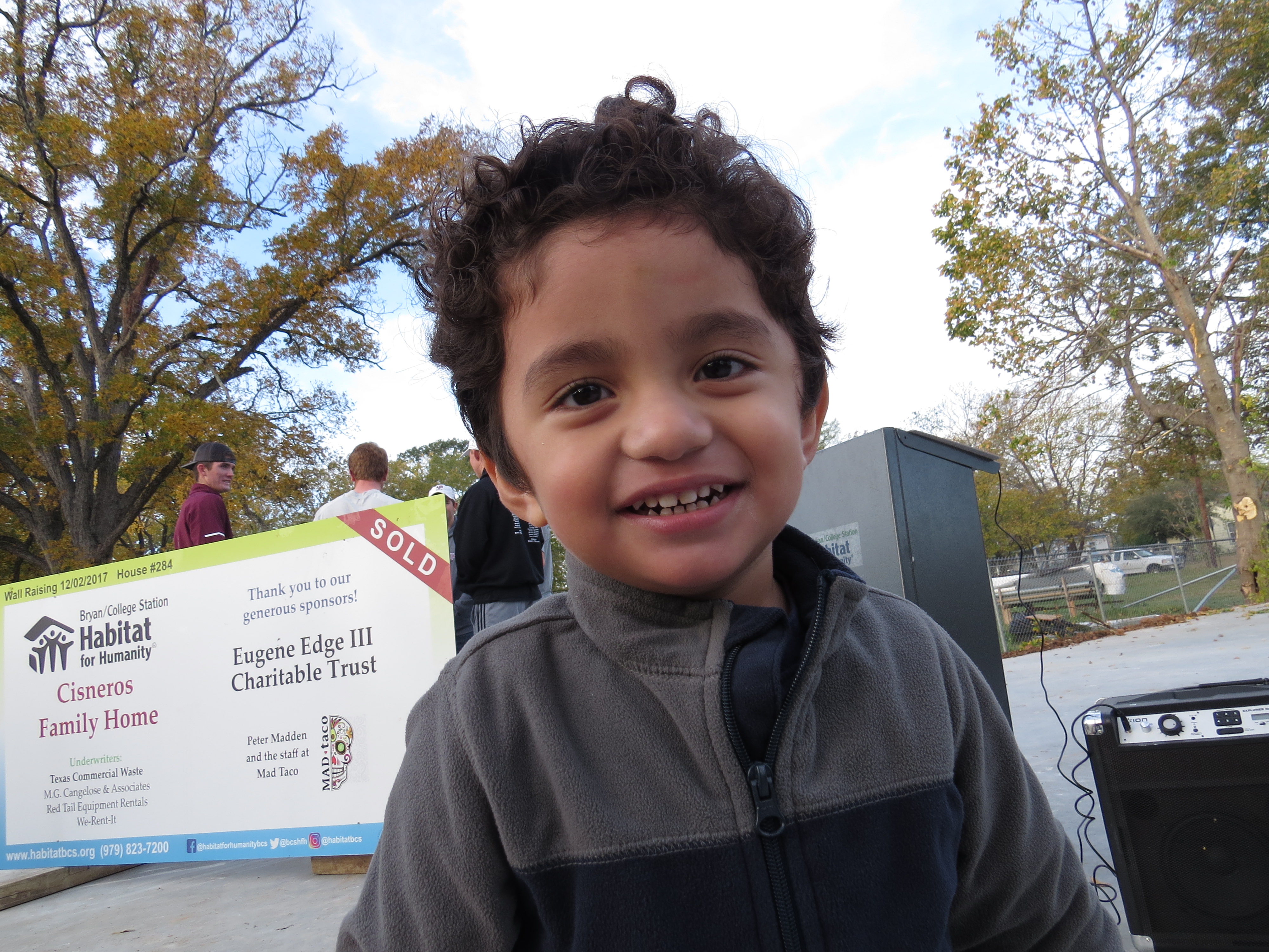 Cisneros' son smiles in front of their future Habitat for Humanity home.